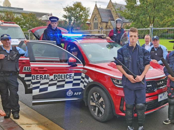 Police and children standing in front of an AFP car