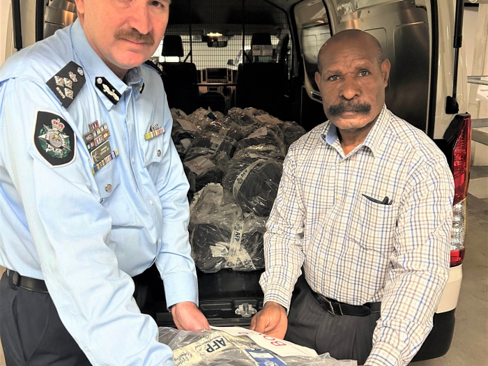 A uniformed officer next to a man in civilian clothing holding a bag of cocaine 