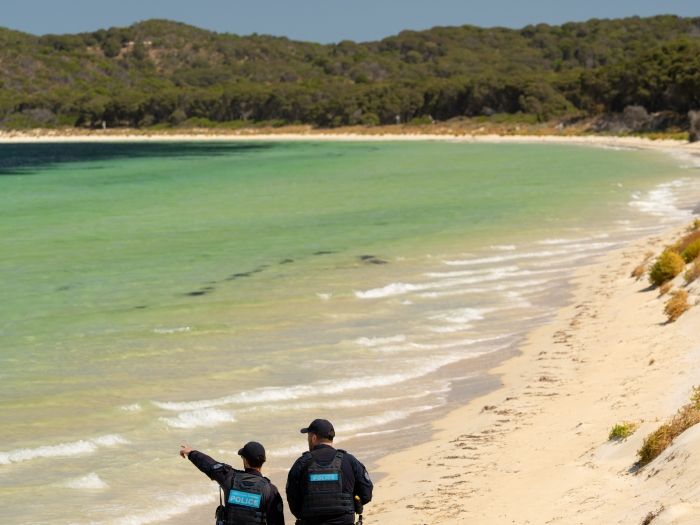 Two police officers walking along a beach in WA