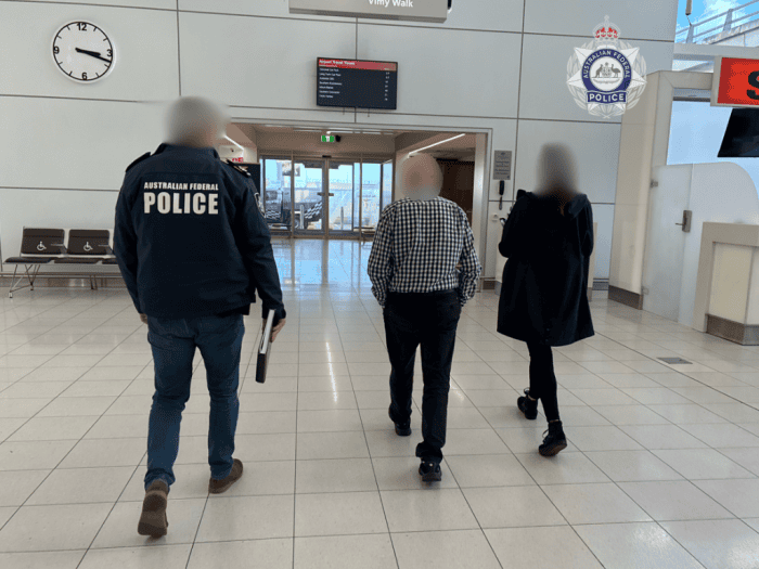 A 74-year-old-man is escorted through an airport