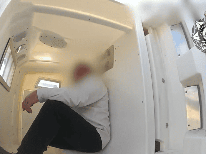 Man sits in the back of a police car