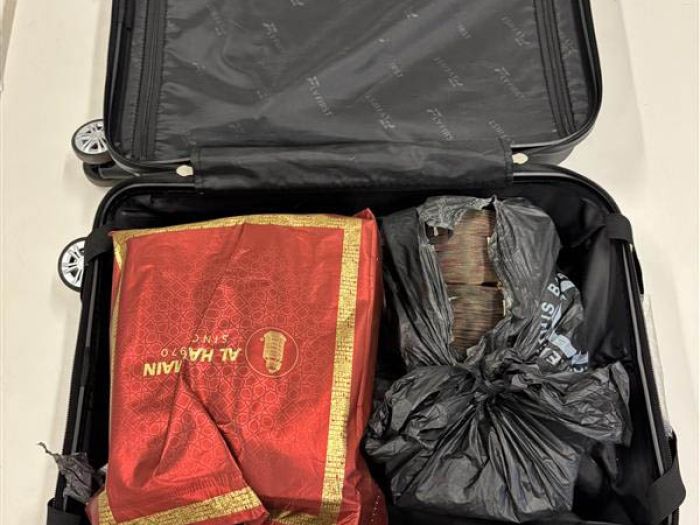 Image of a carry on suitcase opened up to reveal bags of cash found at Perth Airport