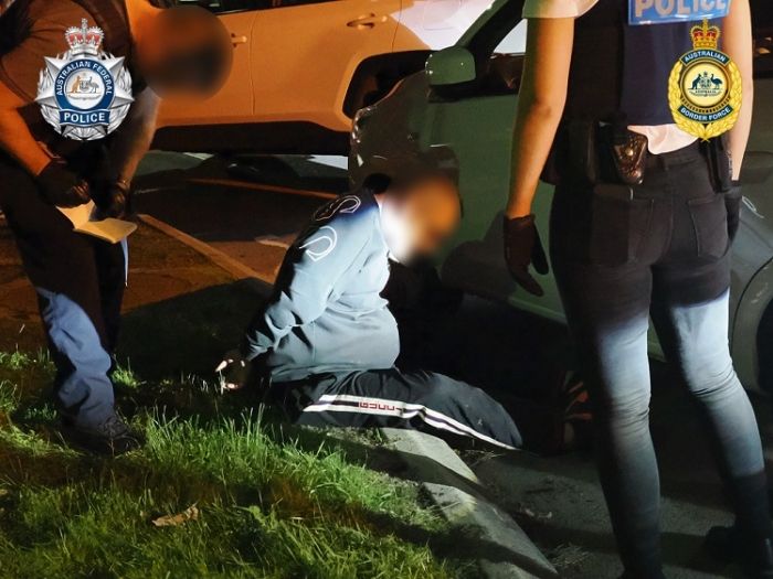 A man sits on a street kerb while under arrest