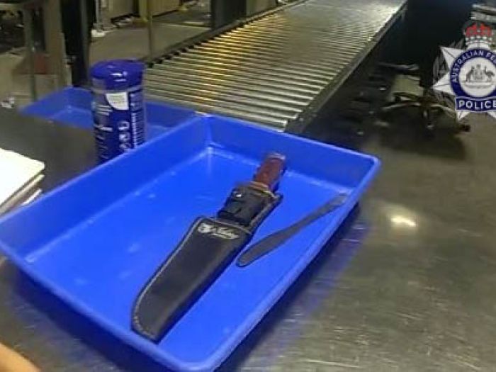 Photo of a large knife in a blue airport security scanning tray