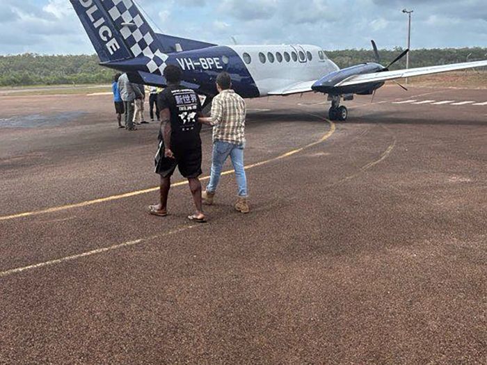 A man is escorted by AFP members to a plane