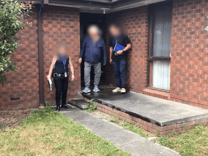 AFP members walk a Victorian man out of a property while under arrest. 