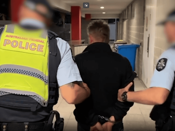 AFP officers walking a Victorian man who was arrested at Perth Airport 