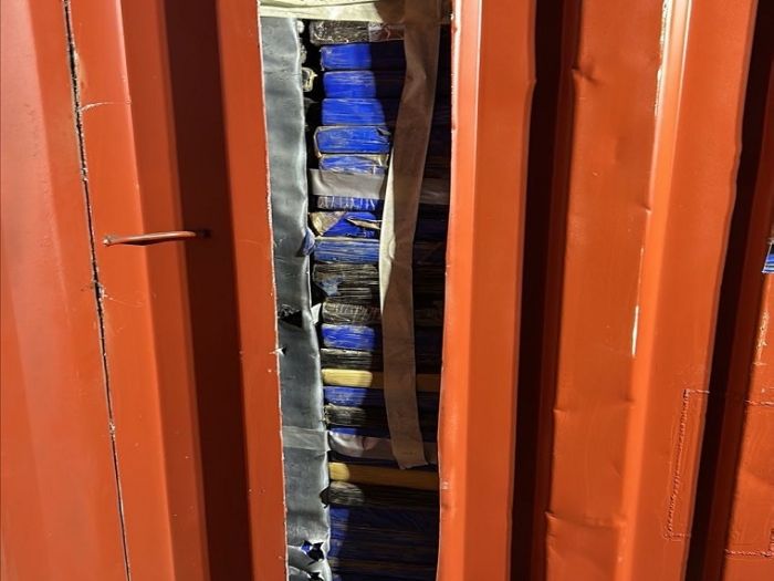 A shipping container opened to reveal packs of cocaine stacked inside
