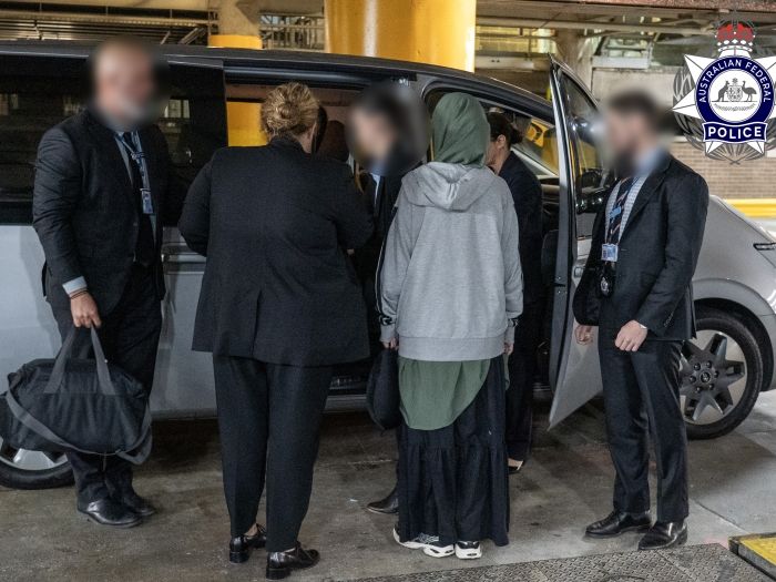A woman is standing next to a car with a number of police officers