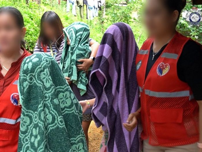 Three children with towels over their heads being guided away