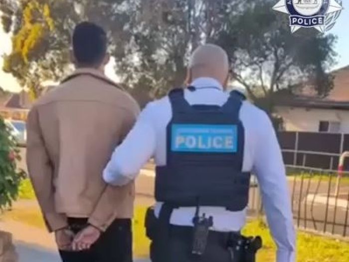 Image of a man being led away in handcuffs by an AFP officer