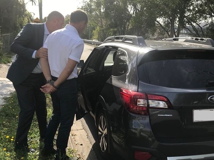 Man in handcuffs being guided into a vehicle
