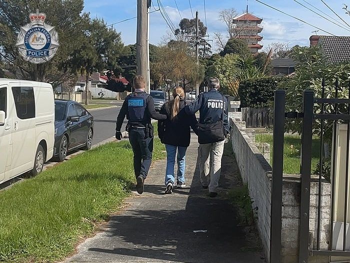 A woman in a black jumped is led away by two AFP officers