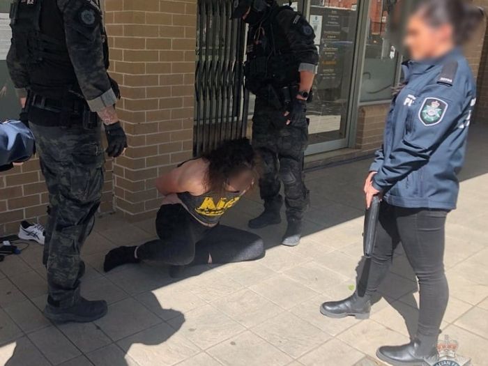 Offender handcuffed on the ground with two specialist police standing over him