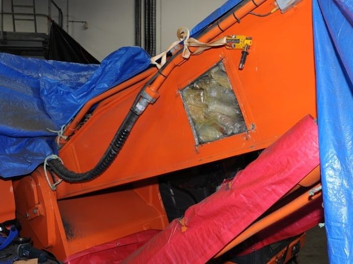 arm of excavator with square hole showing drugs inside