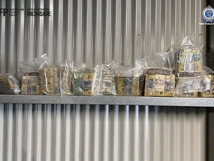 Cash in plastic bags lined up against a metal wall