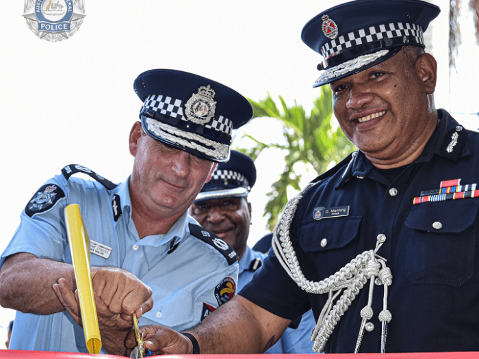 An AFP and PNG police officer cut a red ribbon