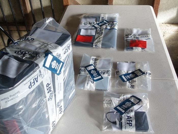 Several electronic items including a laptop and mobile phones are sealed in AFP evidence bags.