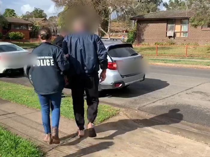 Image of man being led to a car by AFP officers 