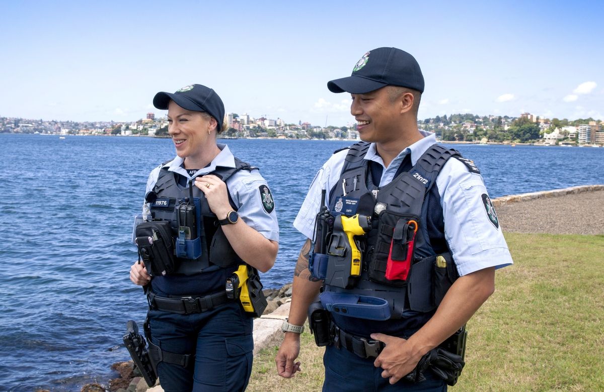 Two police officers walking alongside a lake