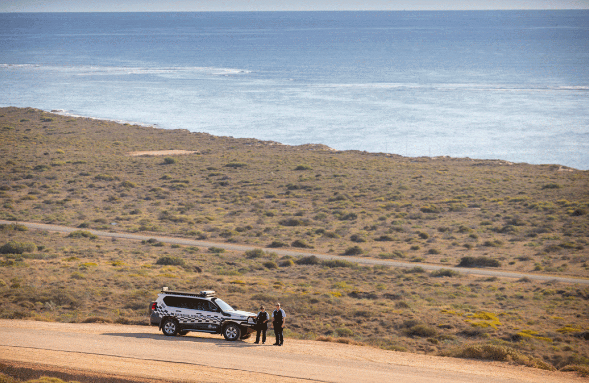 PSO's stood in front of their AFP four wheel drive with ocean behind them