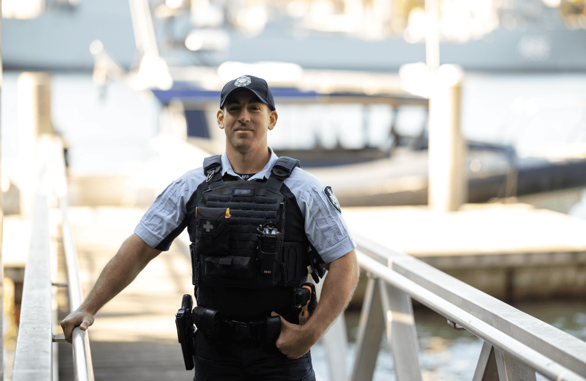 Protective service officer in uniform stands at the end of a dock.
