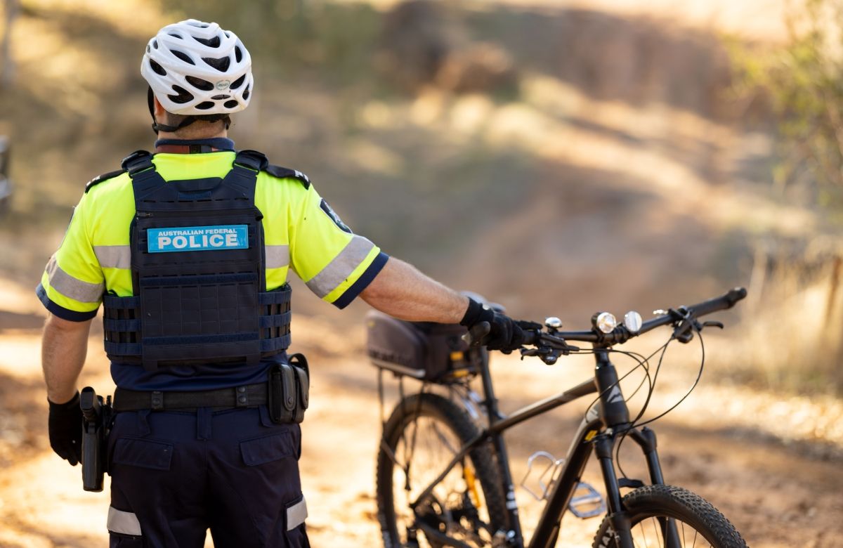 AFP Protective Service Officer holding bike with back to camera