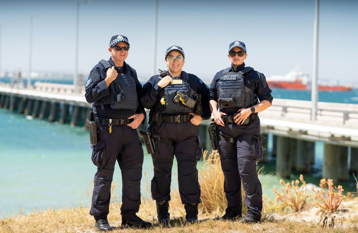 Three AFP Protective Service Officers with a pier and the water behind them