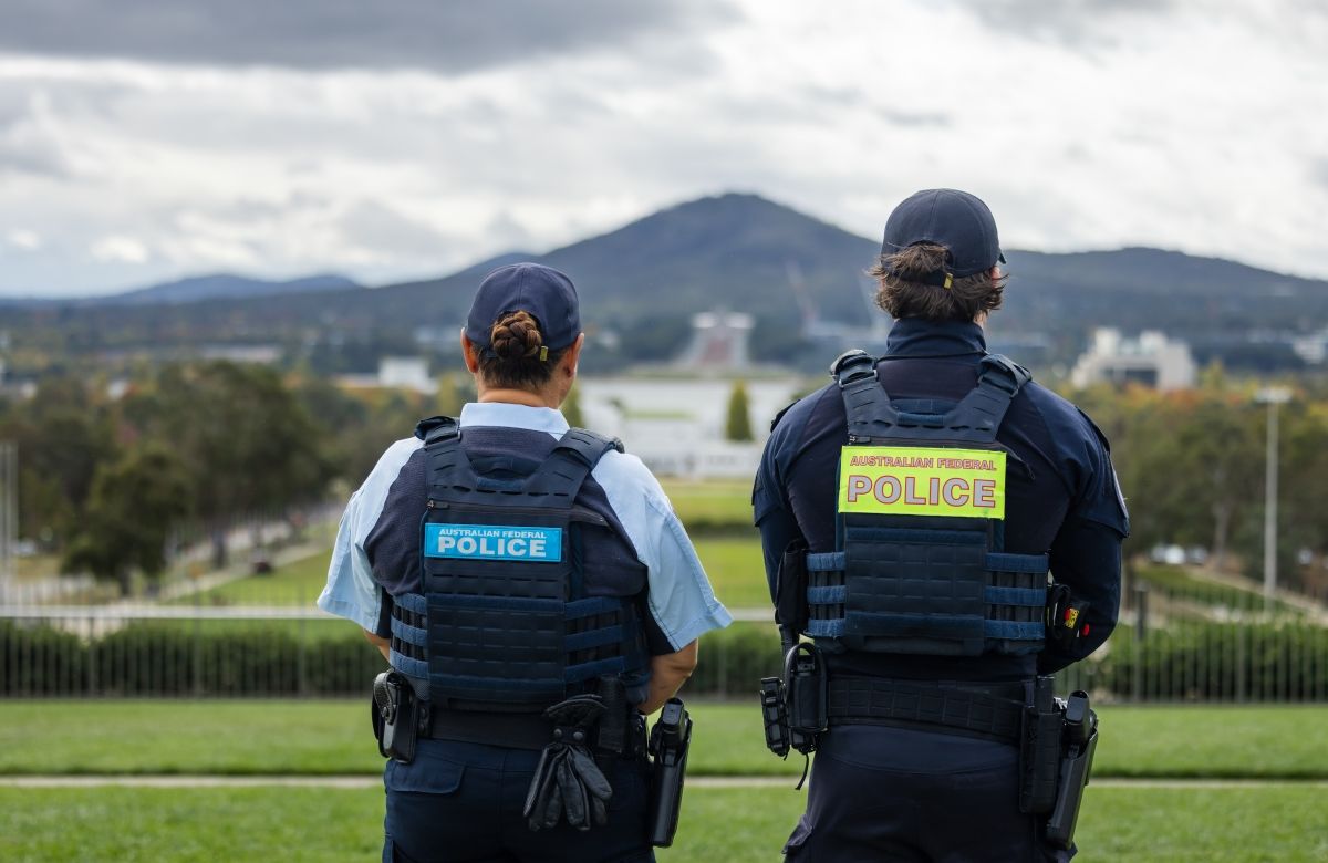 Two AFP Protective Service Officers looking towards the Australian War Memorial with Mount Ainslie in the background