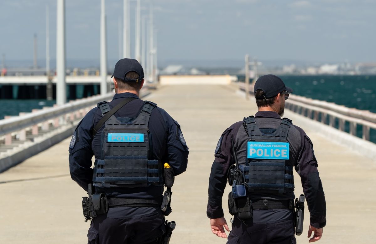 2 AFP Protective Service Officers walking along a pier towards the ocean