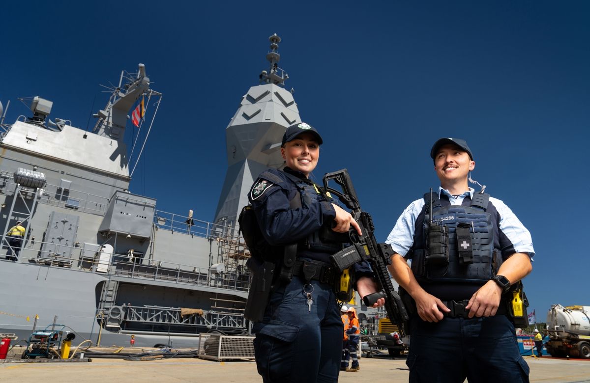 2 AFP Protective Service Officer in front of a navel ship