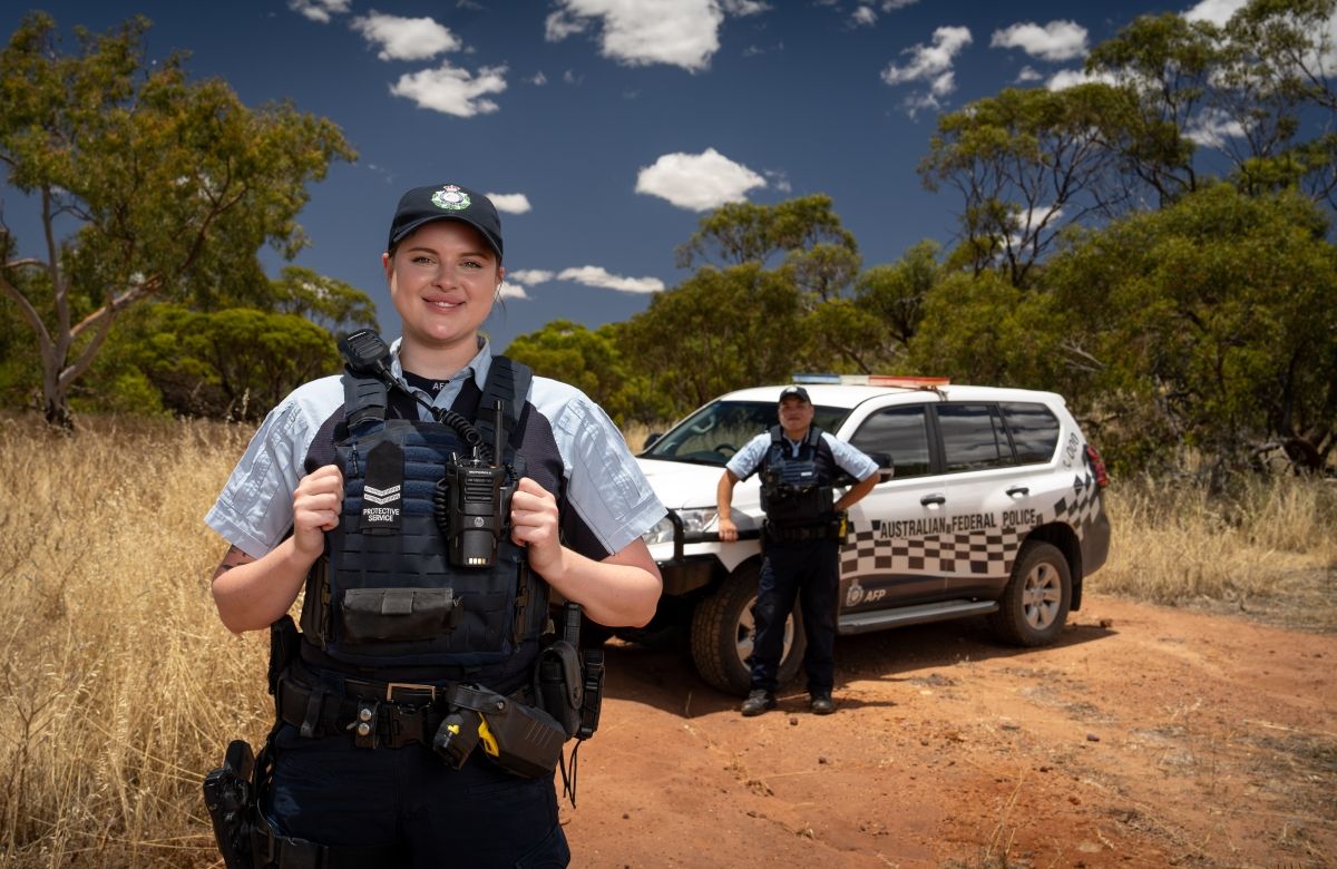 Photograph of two Australian Federal Police Protective Service Officers standing outdoors in front of a vehicle.