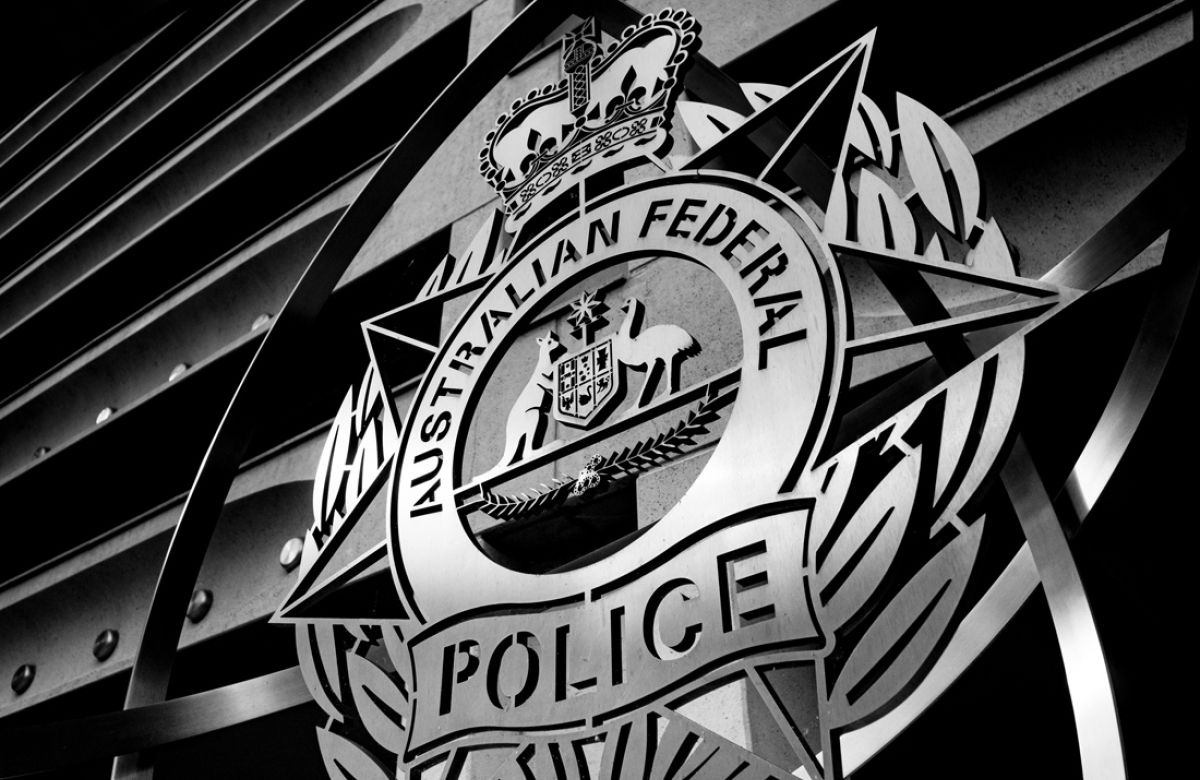 Black-and-white close-up of the Australian Federal Police emblem outside a building.
