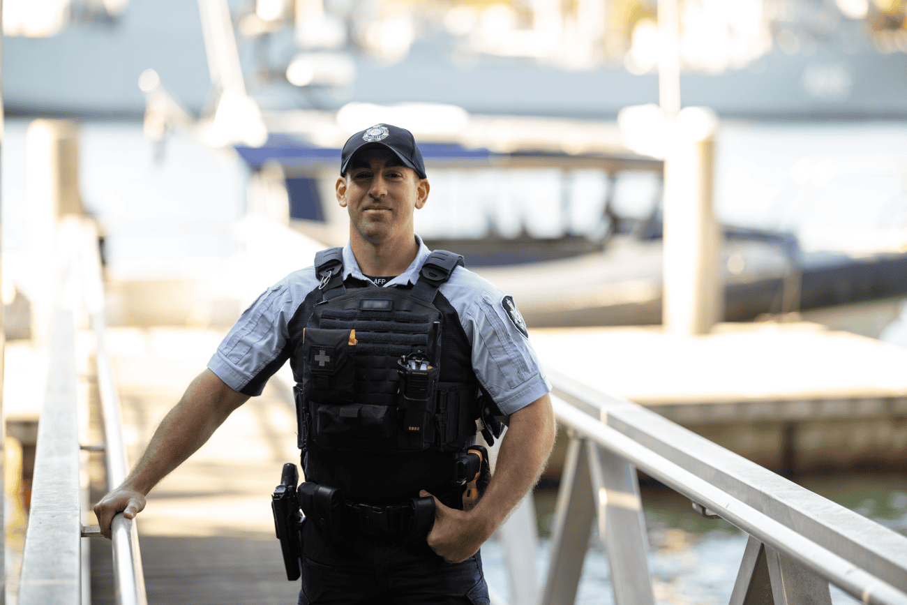 Protective service officer in uniform stands at the end of a dock.
